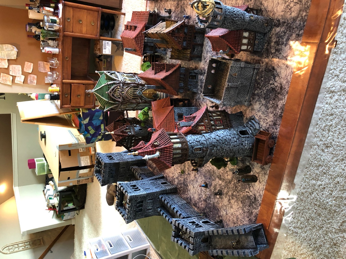 A walled town of painted terrain seen from above: towers, a gate and rows of roofs.